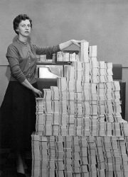 Woman programmer with punched card stack